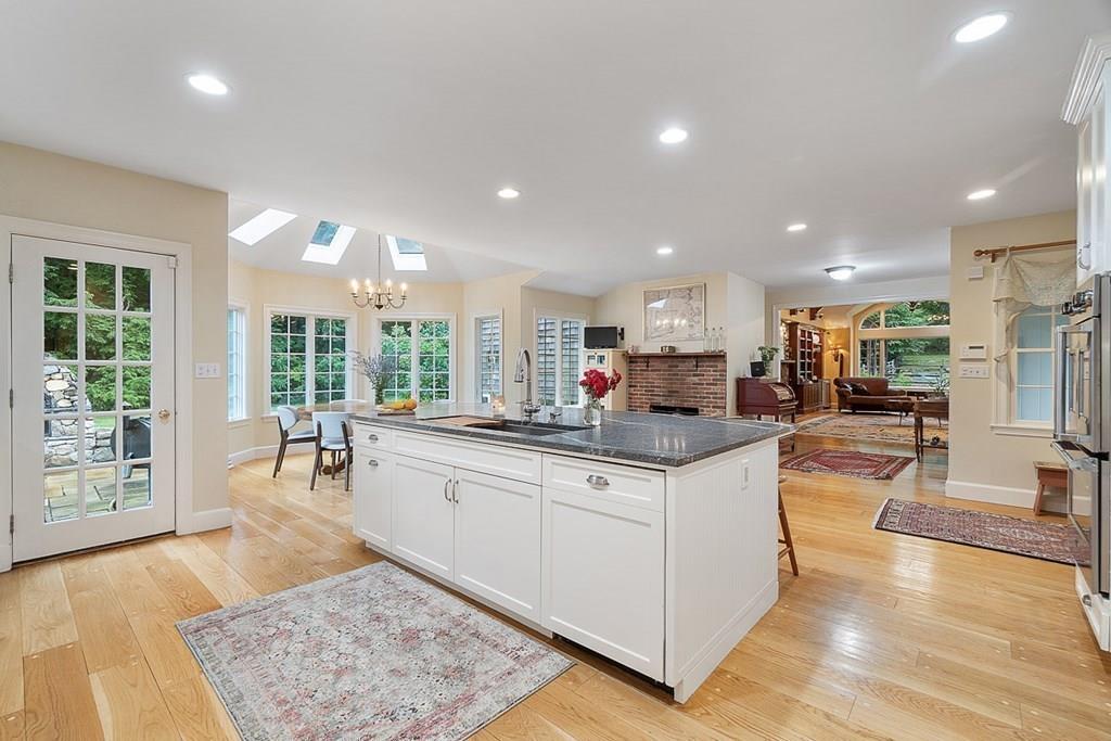 18 Wheeler Road Lincoln, MA 01773 - Photo 8 of 42 a kitchen with stainless steel appliances granite countertop a stove top oven a sink a dining table and chairs with wooden floor