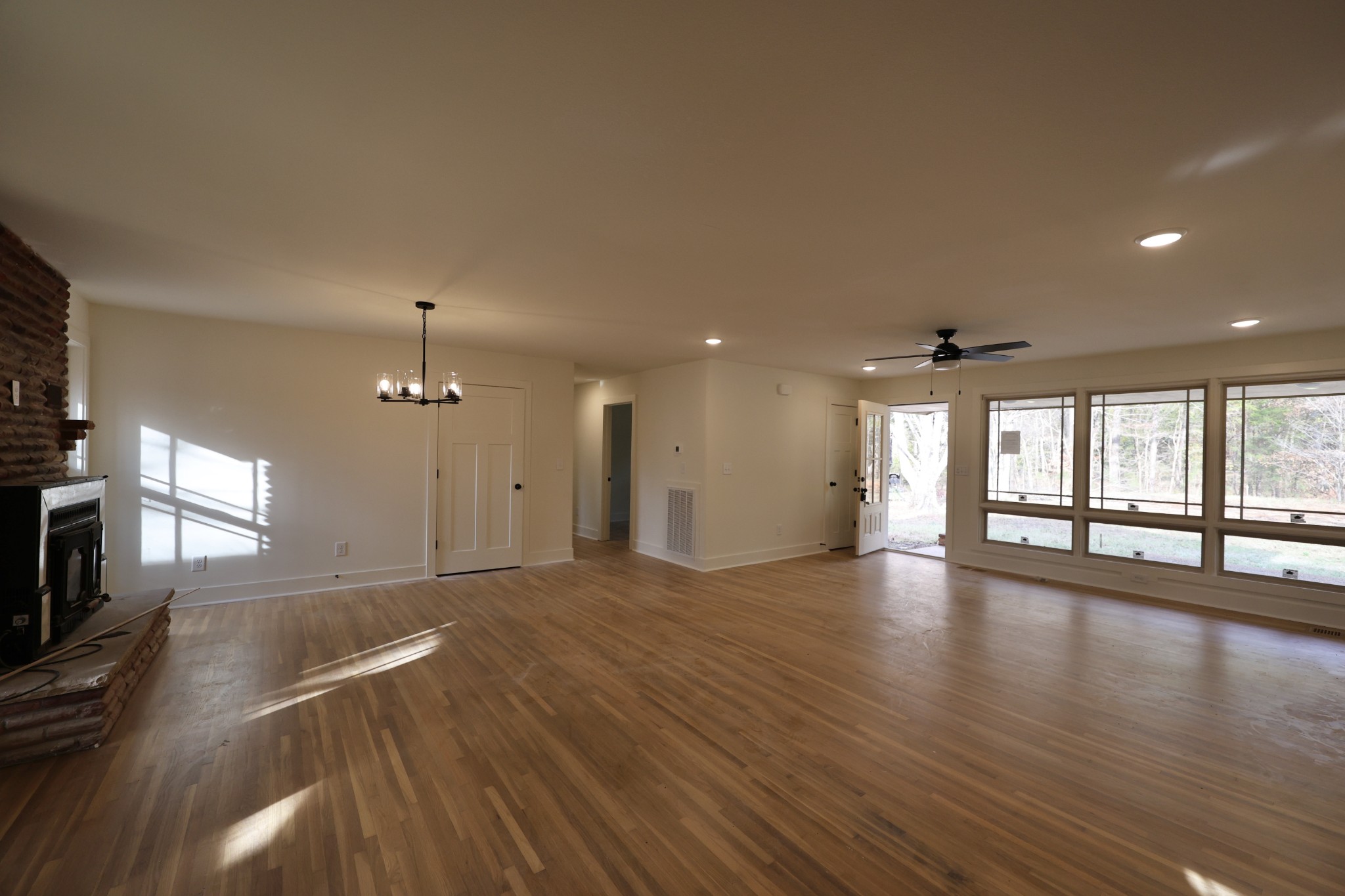 a view of an empty room with wooden floor and a fireplace