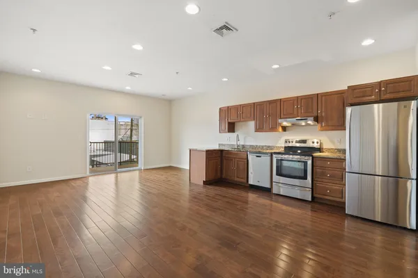 a kitchen with stainless steel appliances a refrigerator and wooden floor