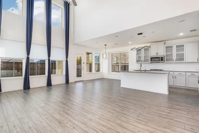 a view of large kitchen with granite countertop a stove top oven a sink and white cabinets with wooden floor