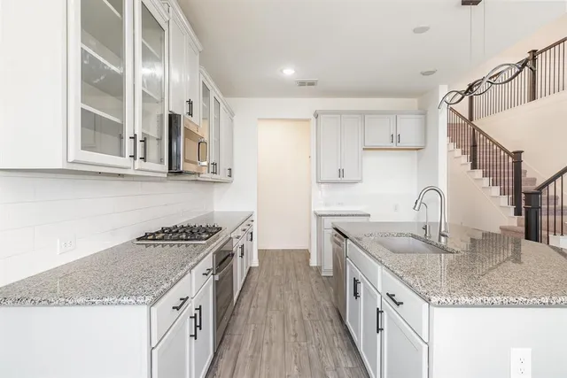 a kitchen with granite countertop a sink a stove and cabinets