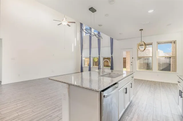a kitchen with stainless steel appliances granite countertop a sink and wooden floor