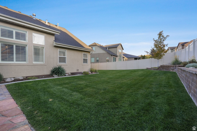 14738 Tangle Hill Road Herriman, UT 84096 - Photo 63 of 66 Spacious green lawn with a full privacy fence, stone paver pathway, and multiple large windows with interior blinds