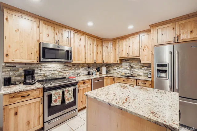 a kitchen with stainless steel appliances granite countertop a refrigerator stove microwave and sink