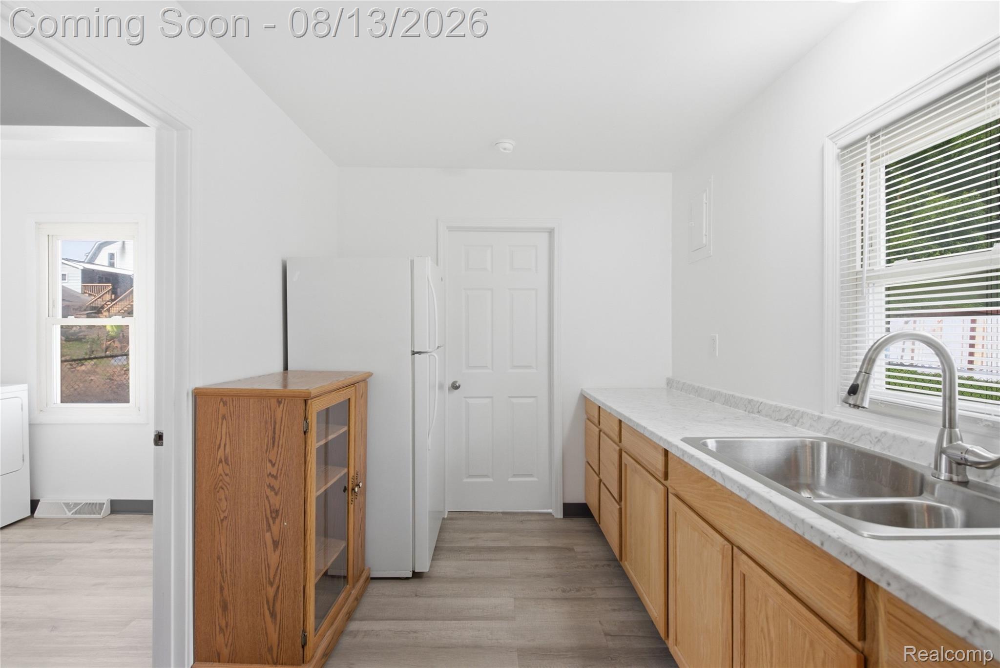 808 Corwin Court Pontiac, MI 48340 - Photo 13 of 33 White walls, wood-finish flooring, light-toned cabinetry, double basin stainless steel sink, and a window with horizontal blinds