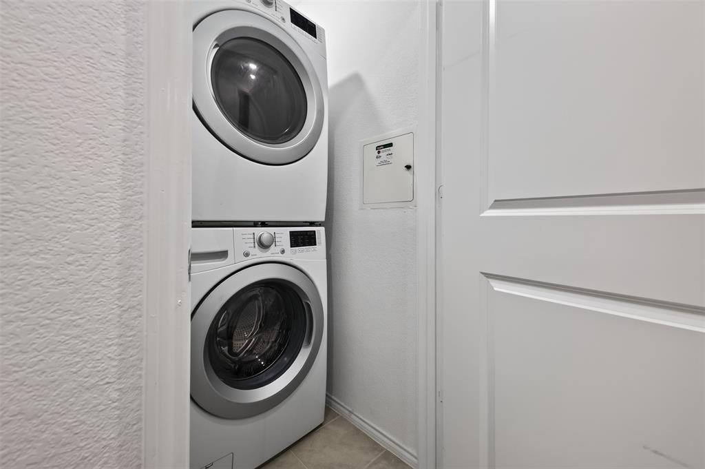 464 Reverie Way Ferris, TX 75125 - Photo 26 of 36 Stackable white washer and dryer units, white paneled interior door, and light-toned floor tiling