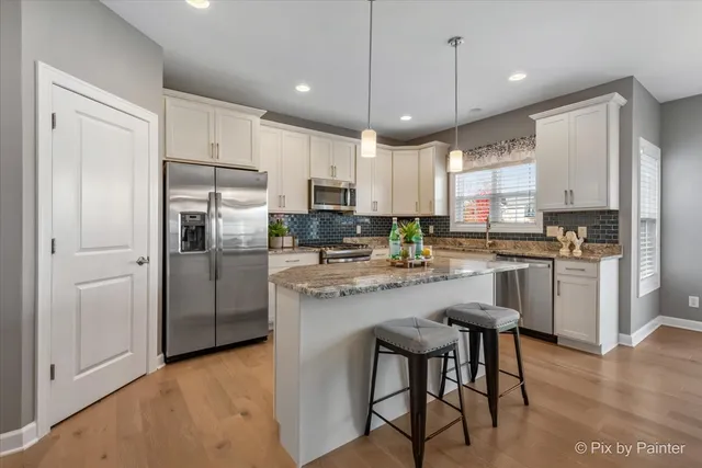 a kitchen with kitchen island a refrigerator a stove a microwave oven a sink with island and chairs