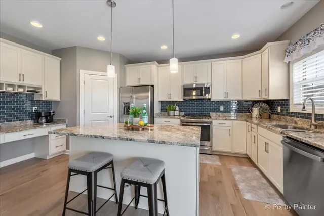 a kitchen with kitchen island granite countertop white cabinets and stainless steel appliances