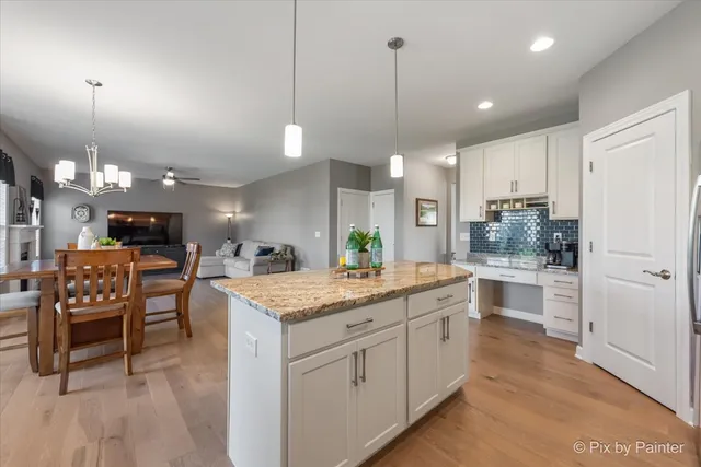 a kitchen with kitchen island granite countertop lots of white cabinets a dining table and chairs
