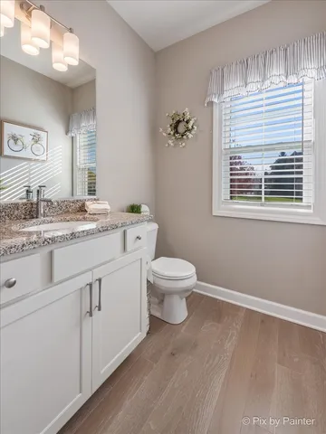 a bathroom with a granite countertop toilet sink and mirror
