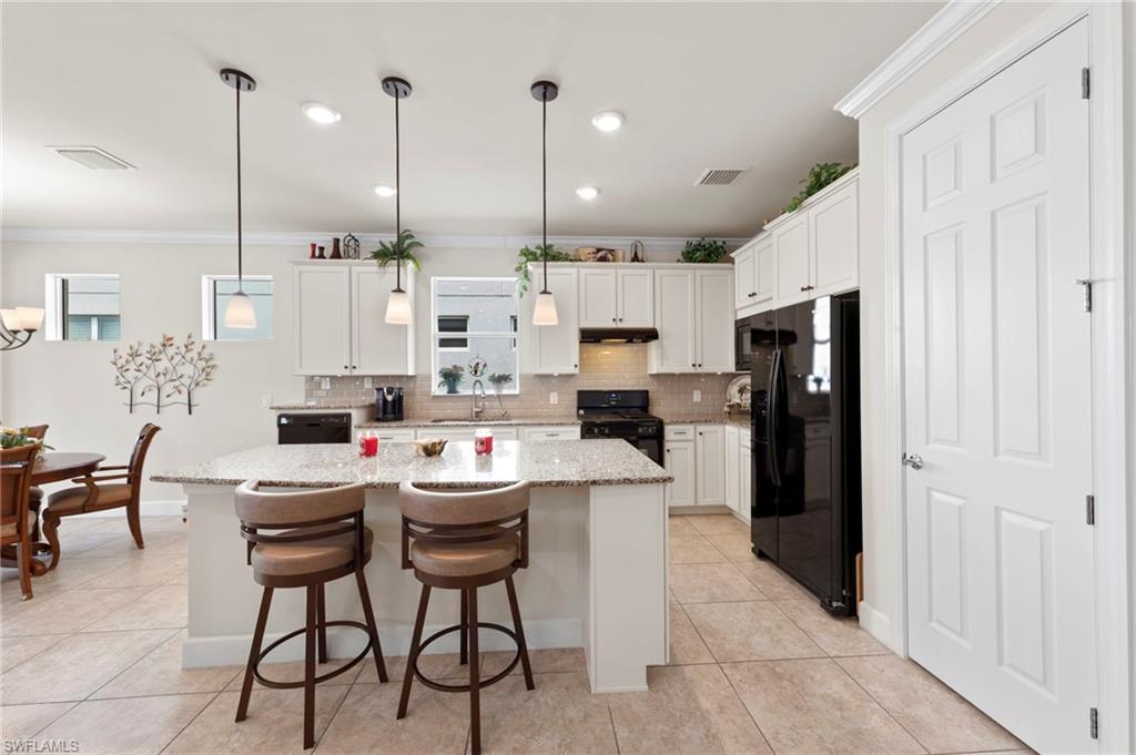 10507 Jackson Square Drive Estero, FL 33928 - Photo 15 of 46 a kitchen with stainless steel appliances kitchen island granite countertop a refrigerator a stove a kitchen island a sink and chairs