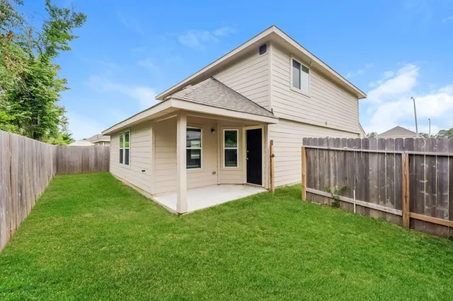 a view of a house with backyard and wooden fence