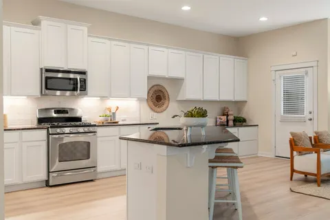 a kitchen with kitchen island granite countertop a sink cabinets and stainless steel appliances