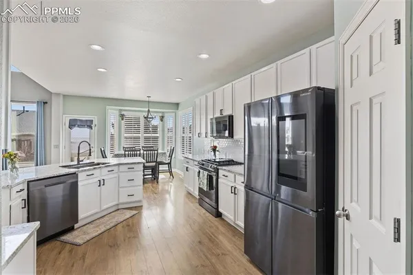 a kitchen with granite countertop stainless steel appliances a refrigerator cabinets and wooden floor
