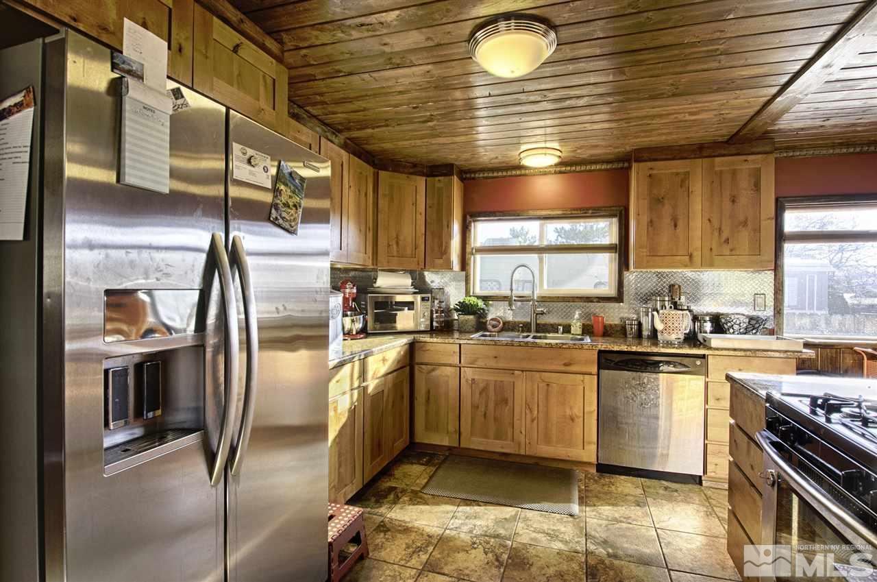 15085 Rhyolite Circle Reno, NV 89521 - Photo 3 of 23 a kitchen with stainless steel appliances granite countertop a sink a stove and a refrigerator