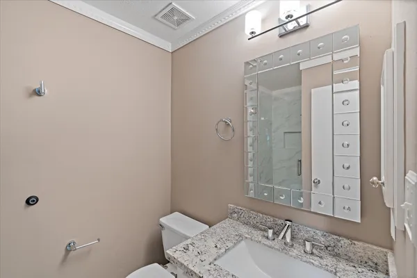 a bathroom with a granite countertop sink a mirror and a toilet