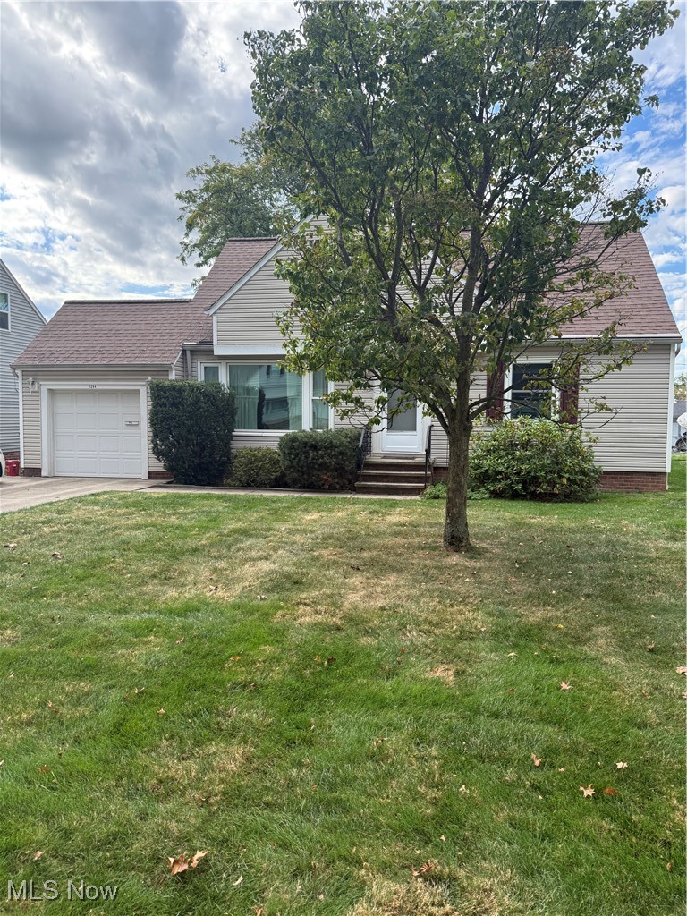 View of property hidden behind natural elements featuring a front yard, an attached garage, and a shingled roof