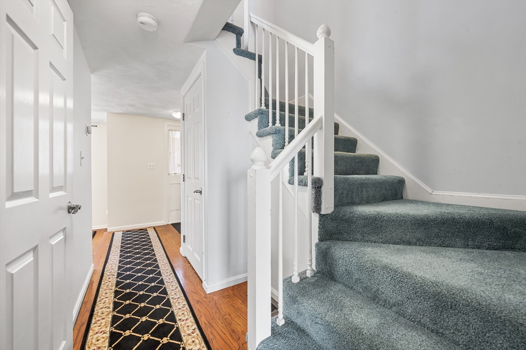 176 Patrick Road, Unit 176 Tewksbury, MA 01876 - Photo 20 of 42 a view of a hallway with wooden floor and staircase
