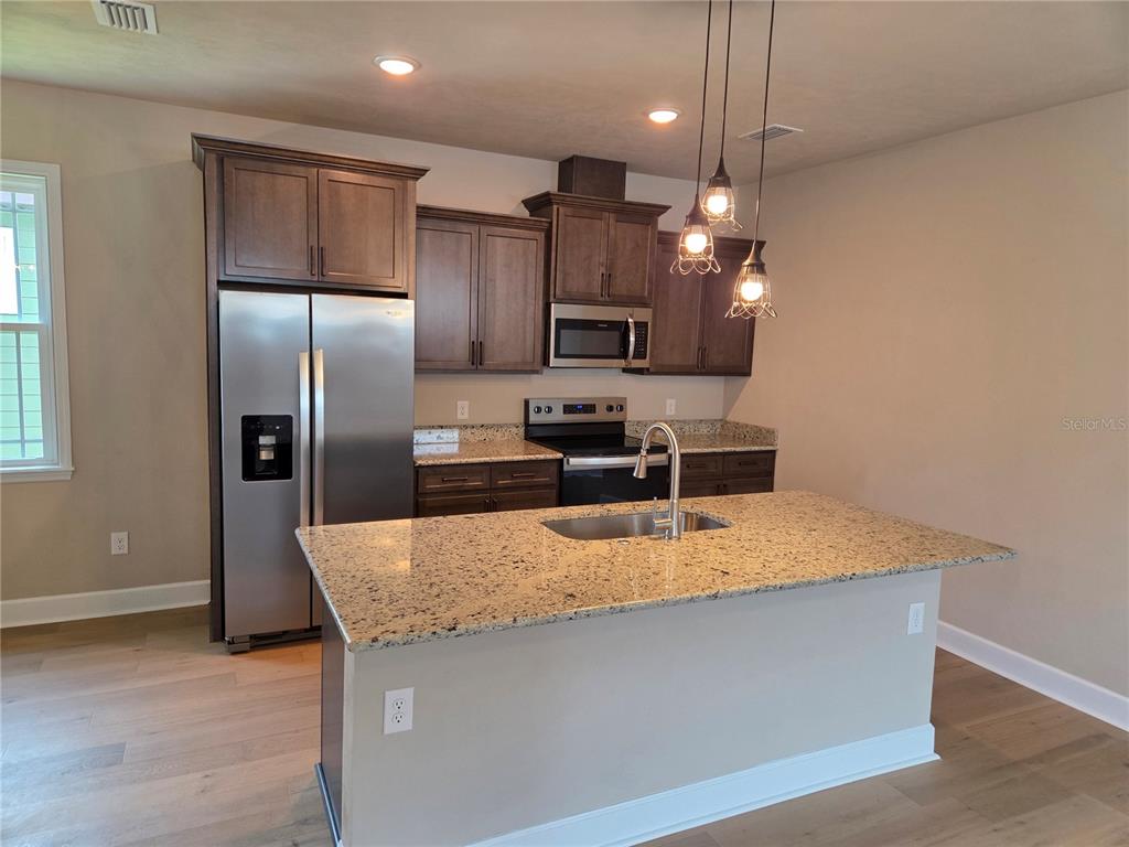 24313 Southwest 17th Lane Newberry, FL 32669 - Photo 4 of 15 a kitchen with kitchen island a counter top space cabinets stainless steel appliances and a window