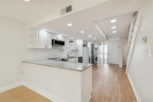 a view of an empty room and kitchen view
