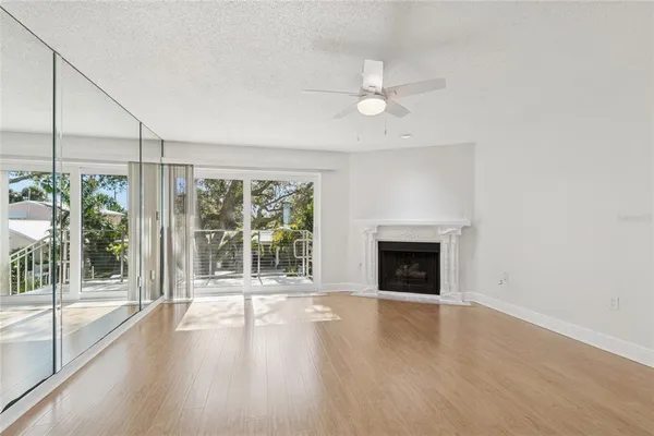 an empty room with wooden floor chandelier fan and windows