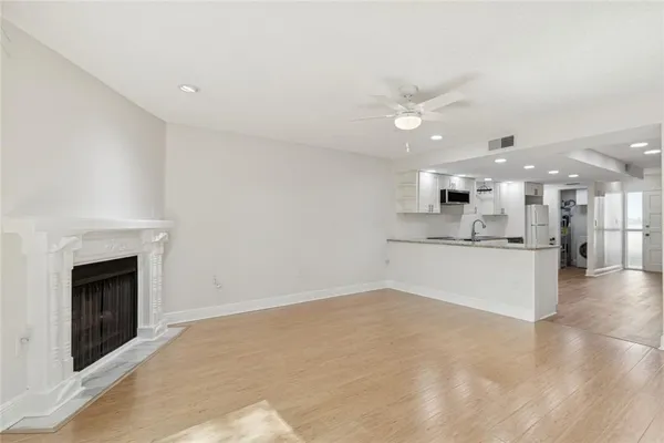 a view of an empty room with wooden floor and a ceiling fan