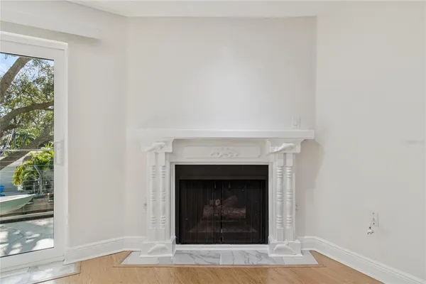 a view of an empty room with wooden floor and a ceiling fan