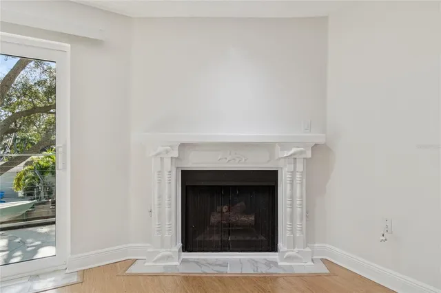 a view of an empty room with wooden floor and a ceiling fan