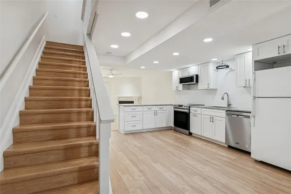 an empty room with wooden floor chandelier fan and windows