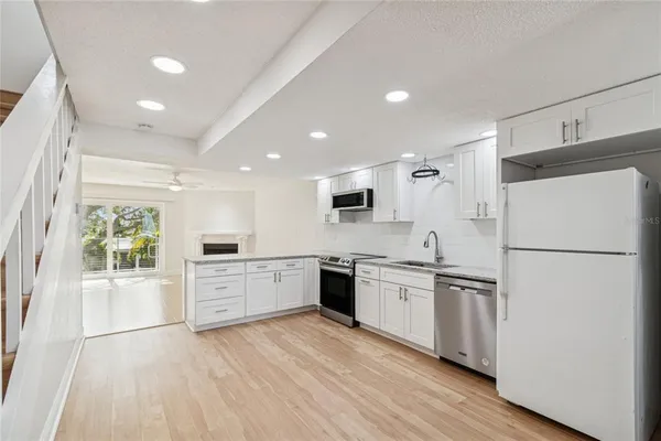 a kitchen with stainless steel appliances a refrigerator a sink a stove top oven a washer dryer and cabinets