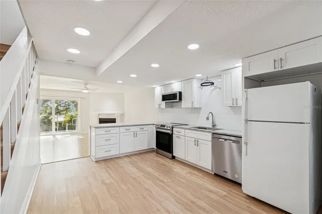 a kitchen with stainless steel appliances a refrigerator a sink a stove top oven a washer dryer and cabinets