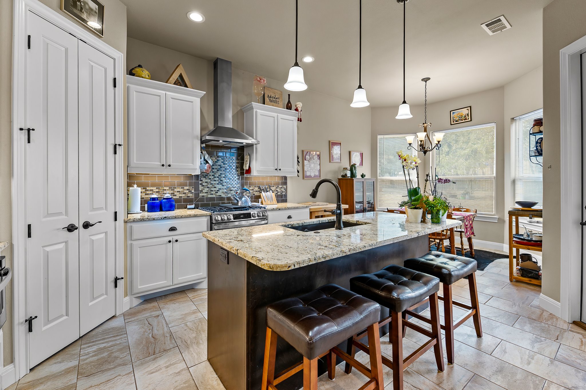 204 Venture Boulevard South Point Venture, TX 78645 - Photo 11 of 40 a kitchen with stainless steel appliances kitchen island granite countertop a table chairs and a refrigerator