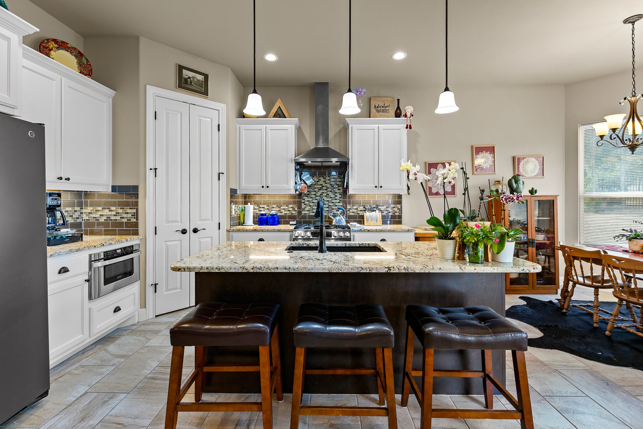 204 Venture Boulevard South Point Venture, TX 78645 - Photo 12 of 40 a room with stainless steel appliances kitchen island granite countertop a dining table chairs and white cabinets