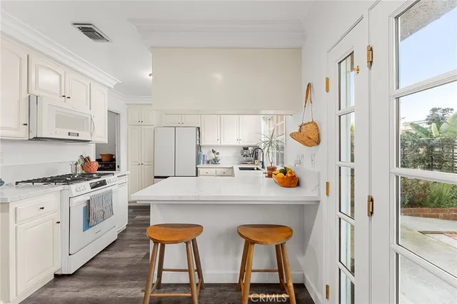 a kitchen with stainless steel appliances a white table chairs and a refrigerator