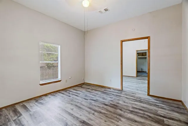 a view of an empty room with wooden floor and a window