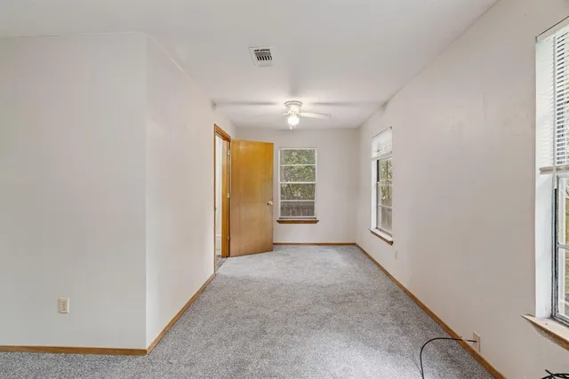 an empty room with windows and chandelier fan