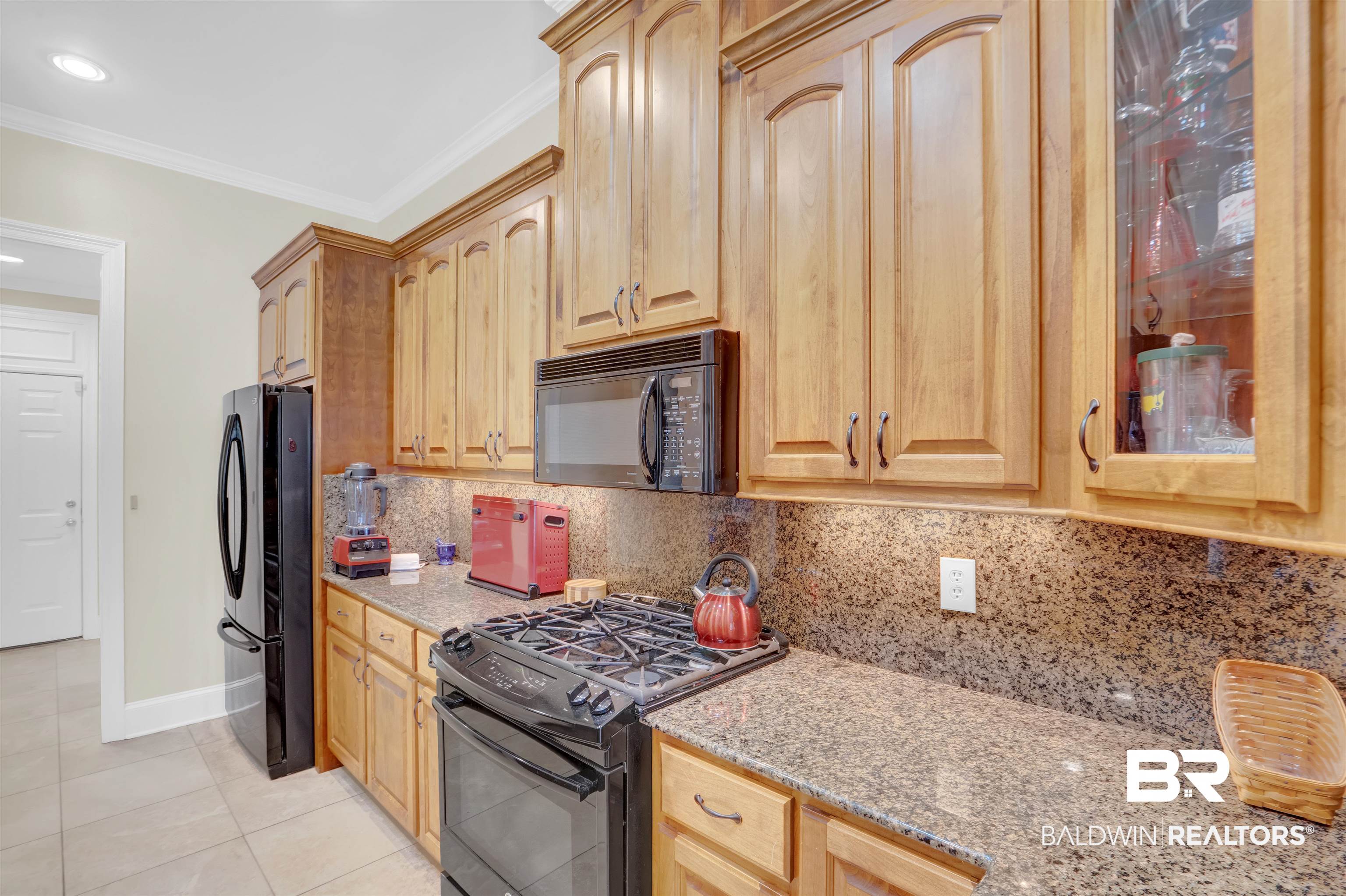 10951 Driver Court Fairhope, AL 36532 - Photo 20 of 46 Kitchen with backsplash, ornamental molding, black appliances, and light stone counters