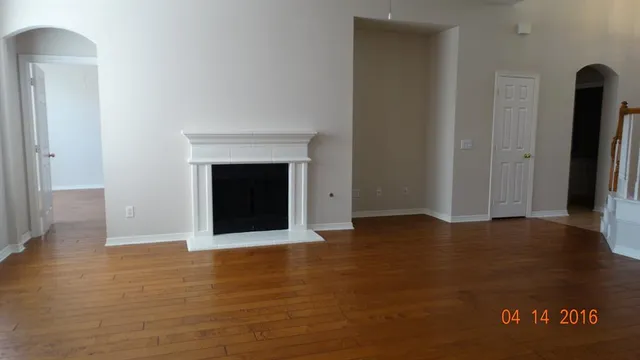 an empty room with wooden floor and fireplace
