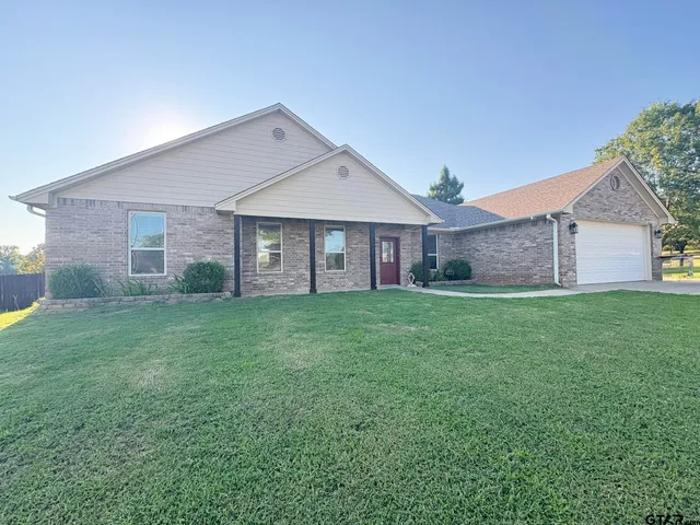 a view of a yard in front of a house with a large tree