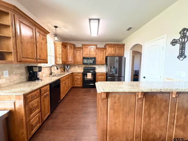 a large kitchen with stainless steel appliances kitchen island granite countertop a sink and cabinets