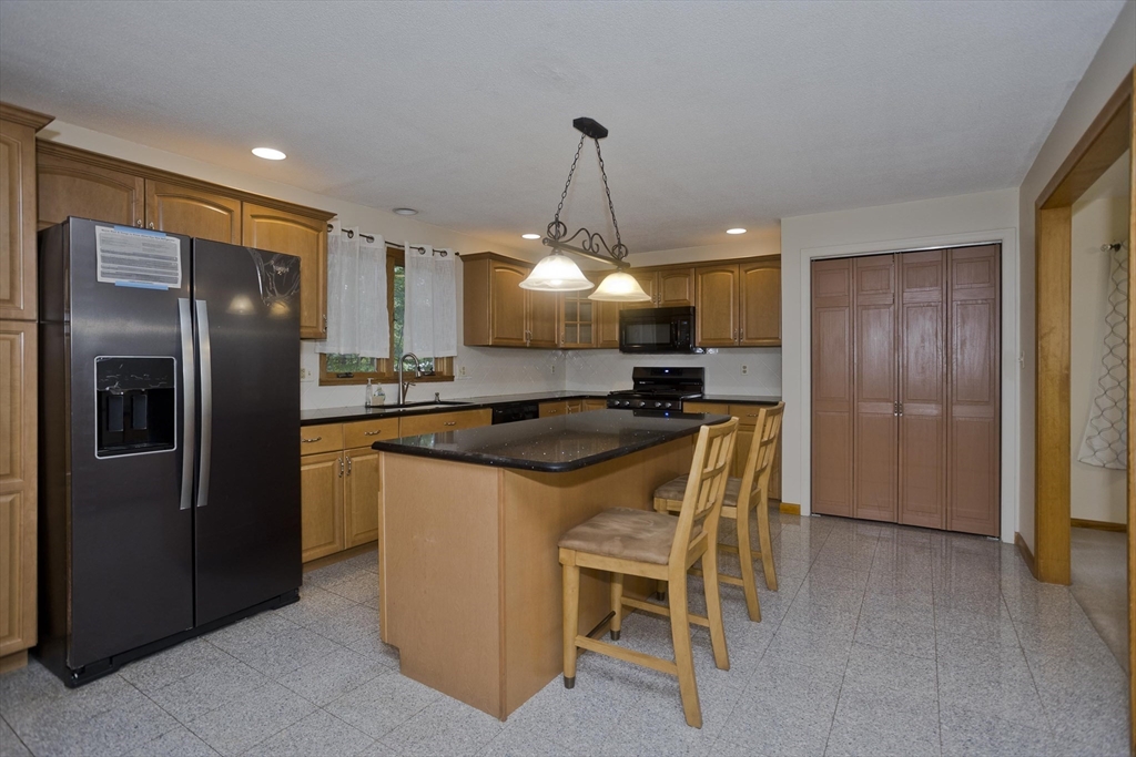 27 Bunker Circle East Longmeadow, MA 01028 - Photo 7 of 36 a kitchen with stainless steel appliances granite countertop a refrigerator a sink a stove a dining table and chairs