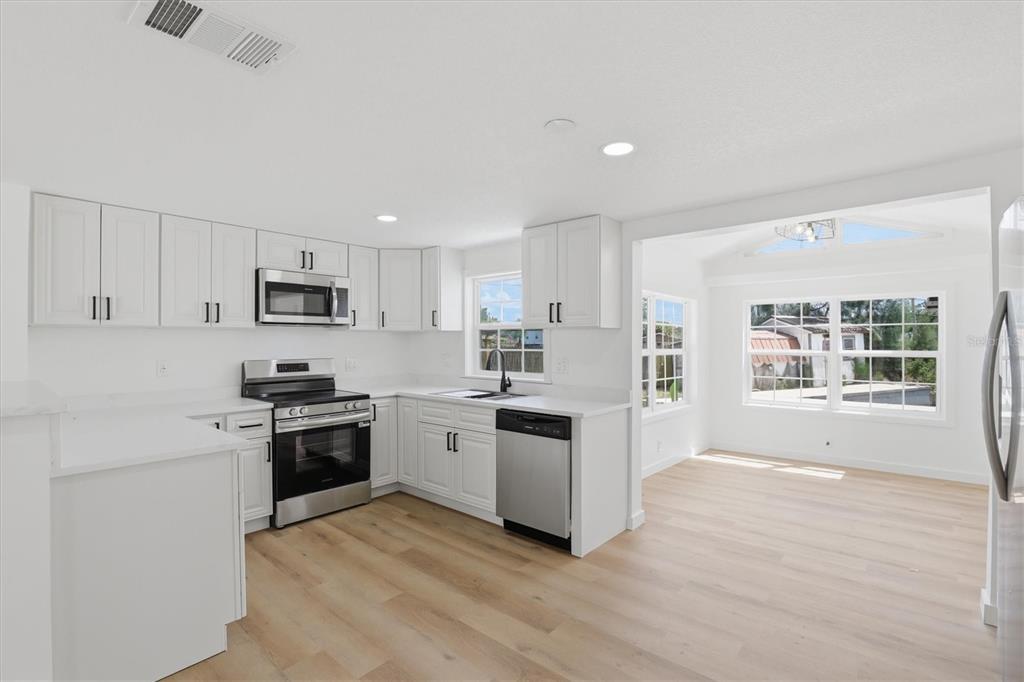 7114 Fair Lane Hudson, FL 34667 - Photo 19 of 59 a kitchen with stainless steel appliances granite countertop a stove a sink dishwasher a refrigerator white cabinets and wooden floor