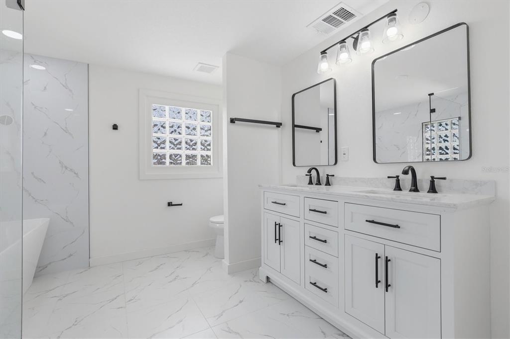 7114 Fair Lane Hudson, FL 34667 - Photo 32 of 59 a bathroom with double vanity sink a mirror and a shower