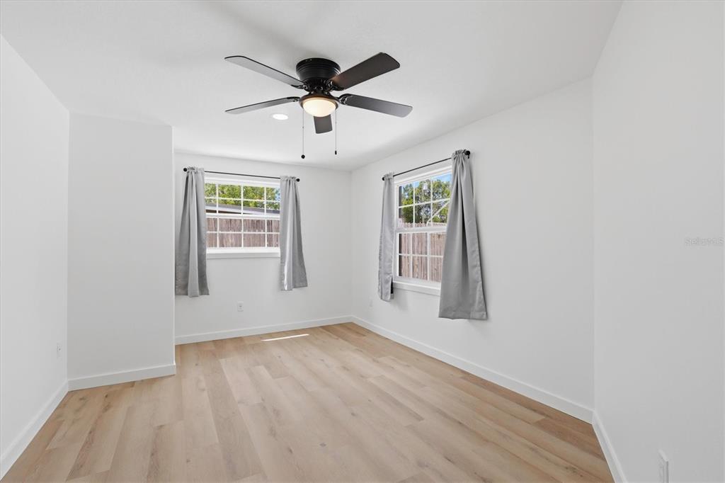 7114 Fair Lane Hudson, FL 34667 - Photo 36 of 59 an empty room with wooden floor chandelier fan and windows