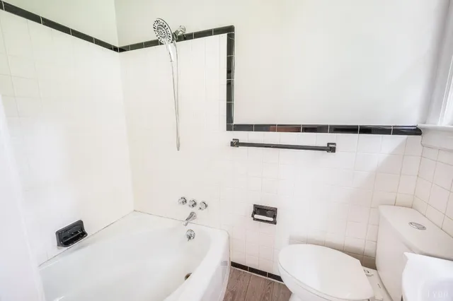 a view of a hallway with wooden floor and a bathroom