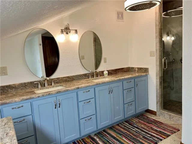 a bathroom with a granite countertop double vanity sink and mirror