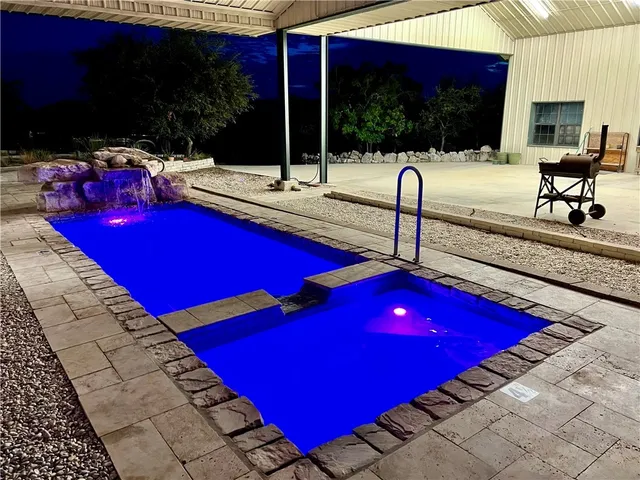 a view of swimming pool with red chairs in patio