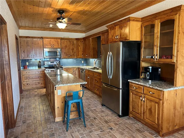 a kitchen with stainless steel appliances granite countertop a refrigerator a stove a sink a dining table and chairs with wooden floor