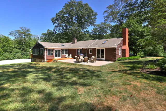 a view of a house with a big yard potted plants and large tree