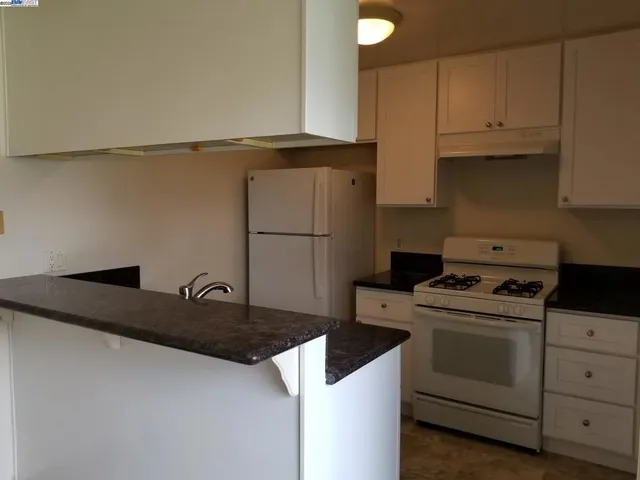 a kitchen with white cabinets and white appliances